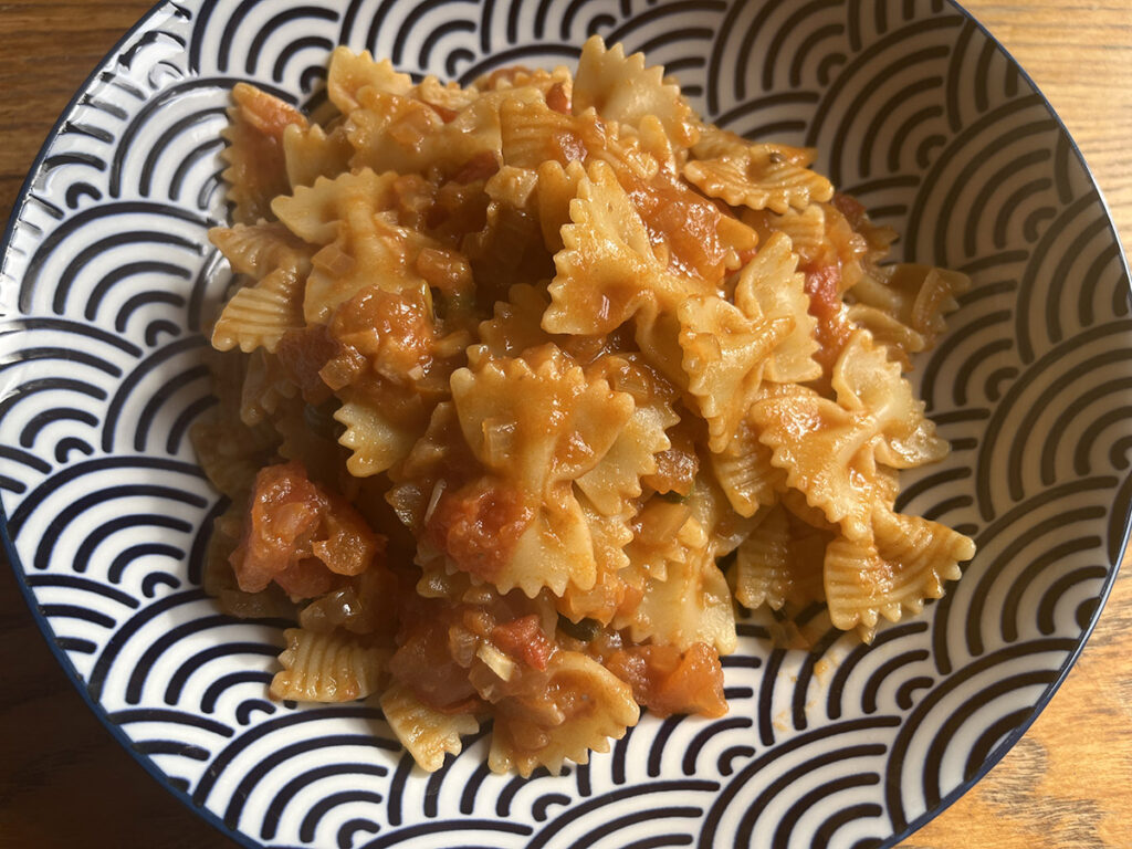 A bowl of delicious and easy olive free puttanesca sauce on a bowl wooden table